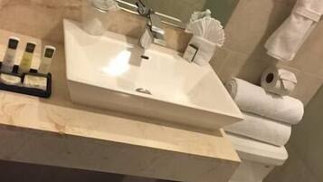 Un baño con lavamanos rectangular, inodoro y cubo de basura.