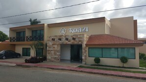 A two-story building with a 'Roazi' sign, featuring a stone facade, a tiled roof, and a balcony on the upper floor.