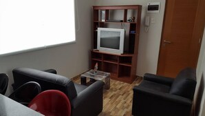 A small living room with a TV, wooden shelves, and a door. - Lima Flats 1 (Lima)