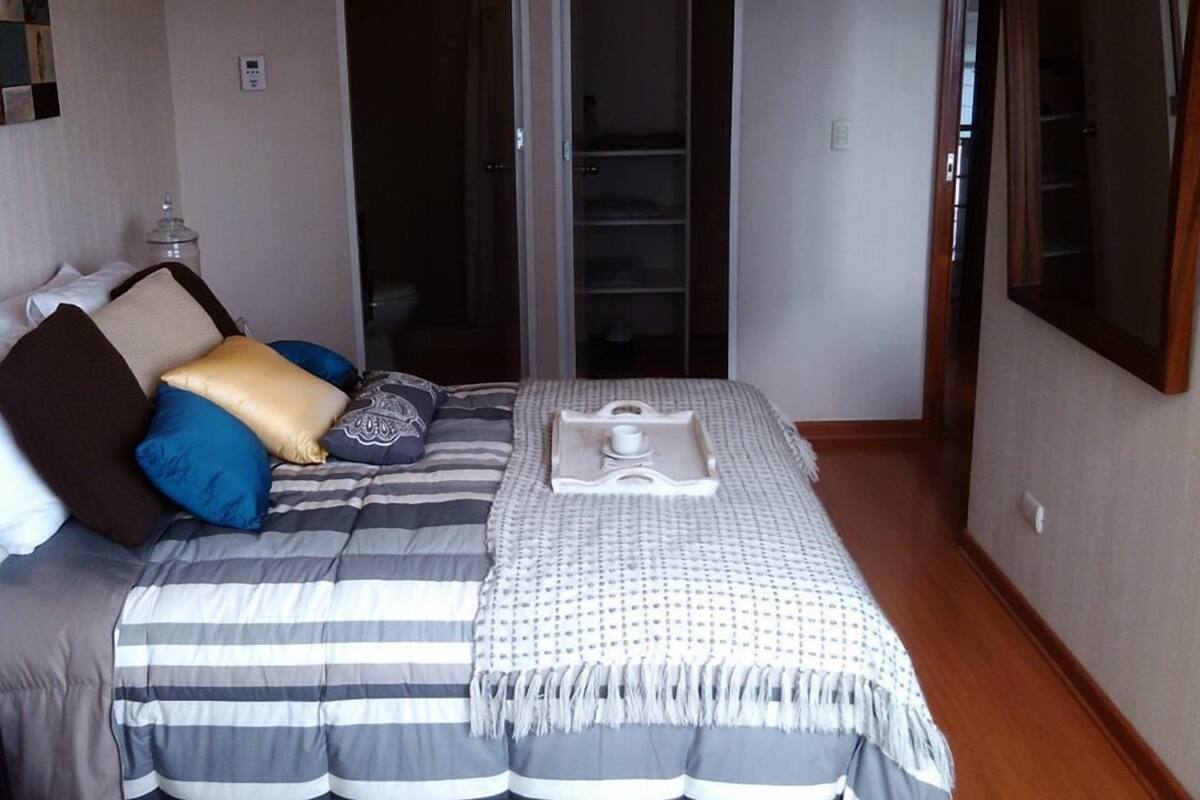 A bedroom with a bed, a bedside table, a mirror, and a closet with sliding doors.