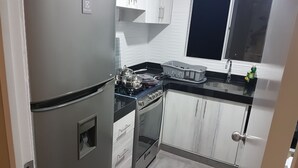 A compact kitchen with a refrigerator, stove, oven, and white cabinets. - Lima Flats 3 (Lima)