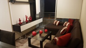 A modern living room with a glass coffee table, a brown sofa with red cushions, and a white cabinet with decorative items. - Lima Flats 3 (Lima)