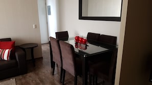A dining area with a glass table, brown chairs, and a red apple centerpiece. - Lima Flats 3 (Lima)