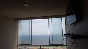 A room with a large window overlooking a beach and the ocean. - Lima Flats 3 (Lima)