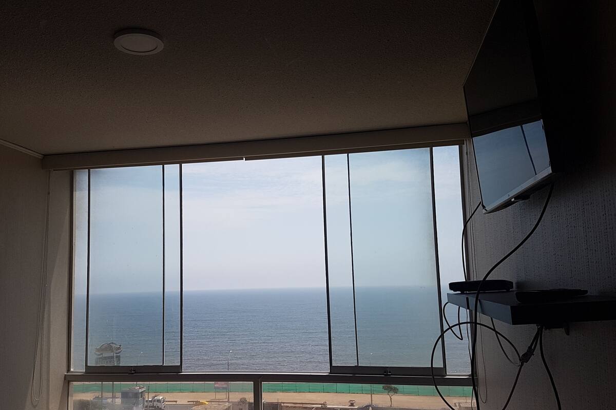 A room with a large window overlooking a beach and the ocean.