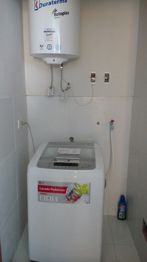A water heater with a control panel, a power outlet, and a water filter bottle on the floor.