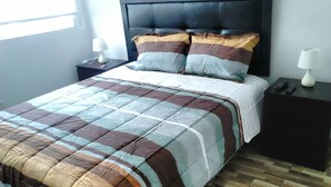 A bed with a checkered bedspread, a dark headboard, and two bedside tables with lamps. - Lima Flats 4 (Lima)