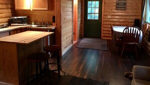 Ein gemütliches Blockhaus-Interieur mit Küche, Essbereich und einer grünen Tür.