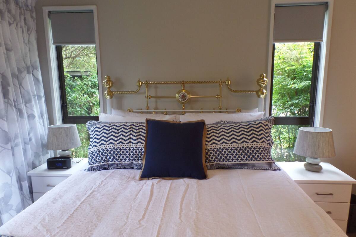 A neatly made bed with patterned pillows, a gold headboard, and two bedside lamps.