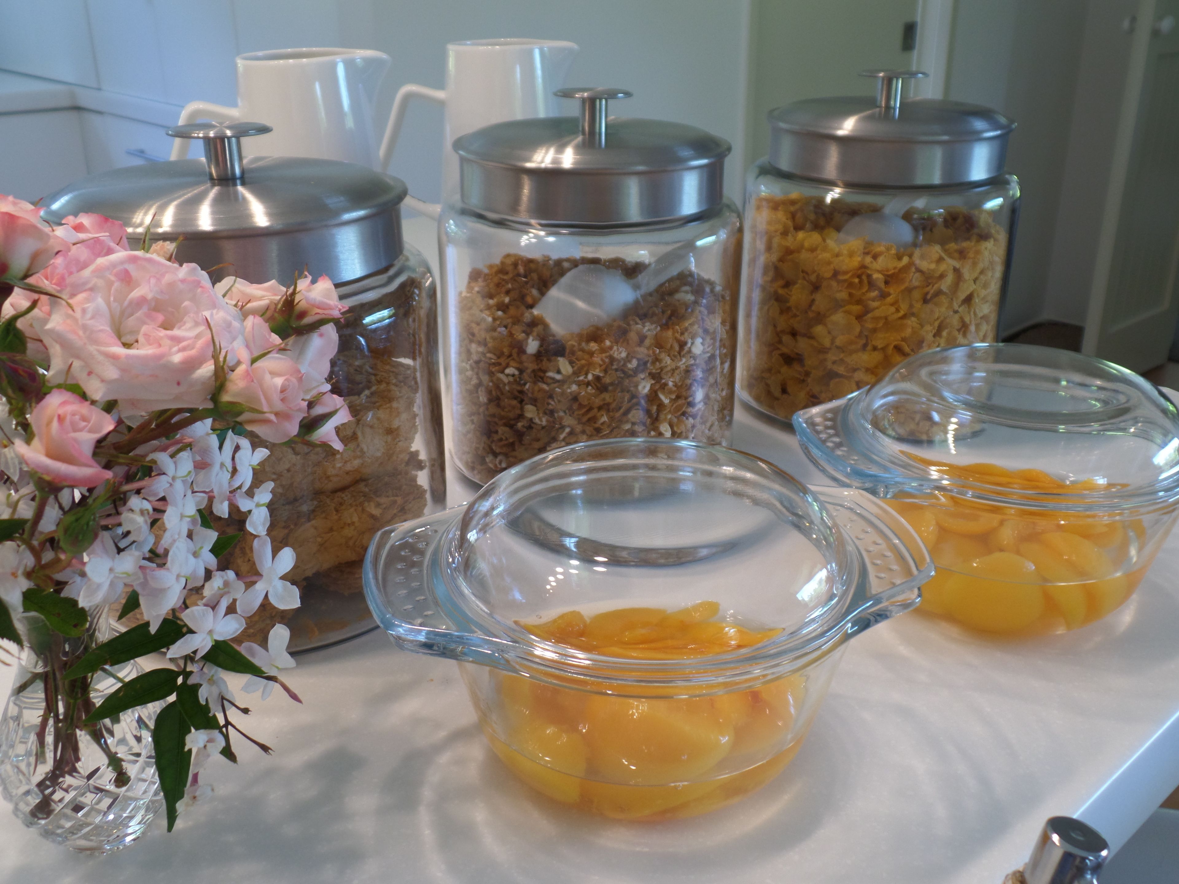 A buffet table with various food items and a vase of flowers.