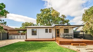 A modern single-story house with a covered patio, a small deck, and a well-maintained lawn. - Sea Devine (Port Willunga)