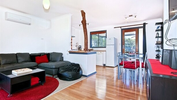 A modern living space with a sofa, coffee table, and a dining area with chairs and a table. - Sea Devine (Port Willunga)