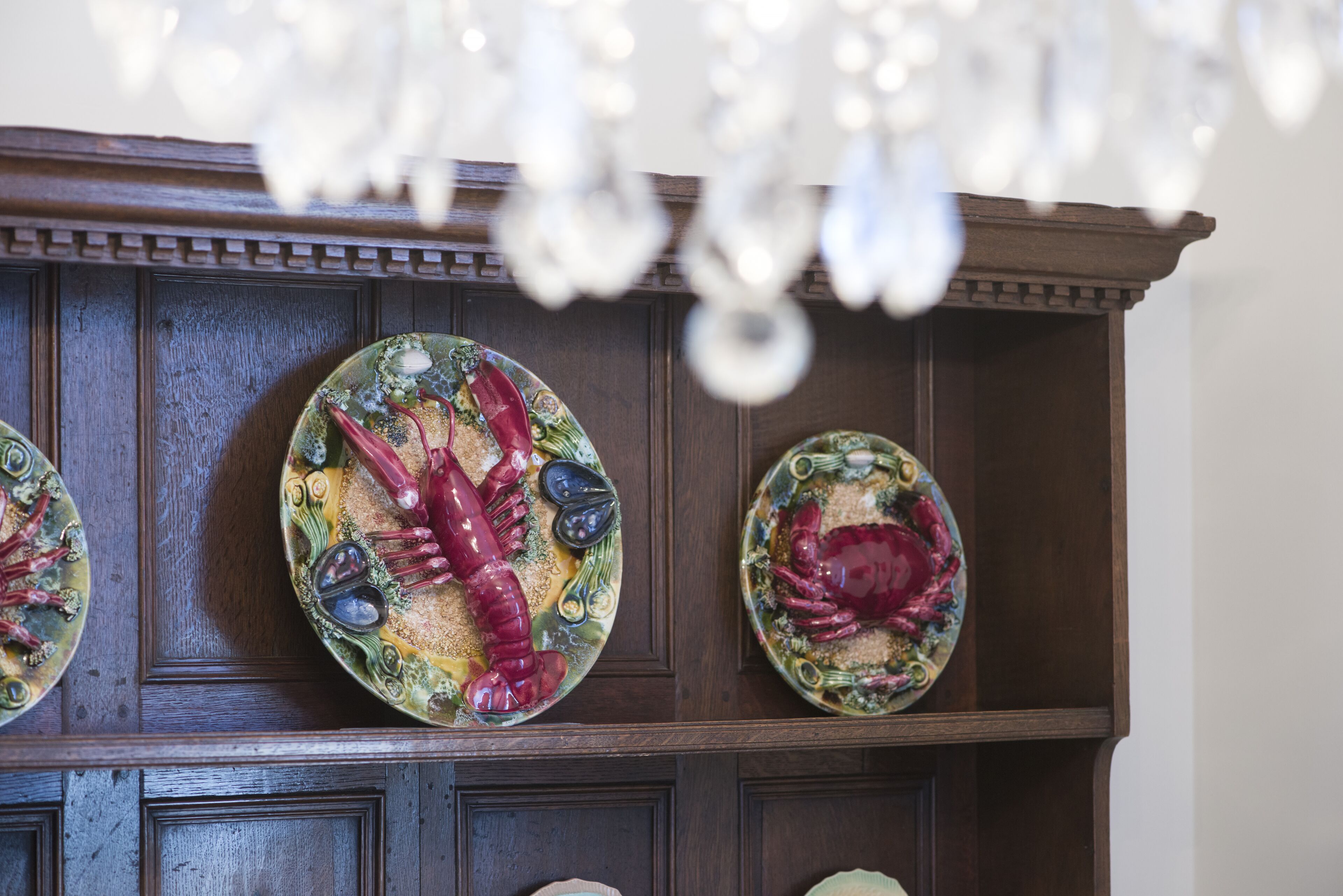 A wooden cabinet with decorative plates featuring lobster designs.