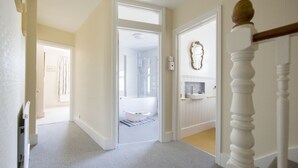 Un pasillo con una puerta blanca que da a un baño con bañera.