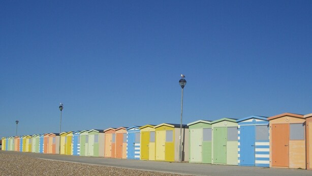 Una hilera de cabañas de playa coloridas bajo un cielo despejado.