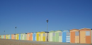 Eine Reihe bunter Strandhütten unter blauem Himmel.