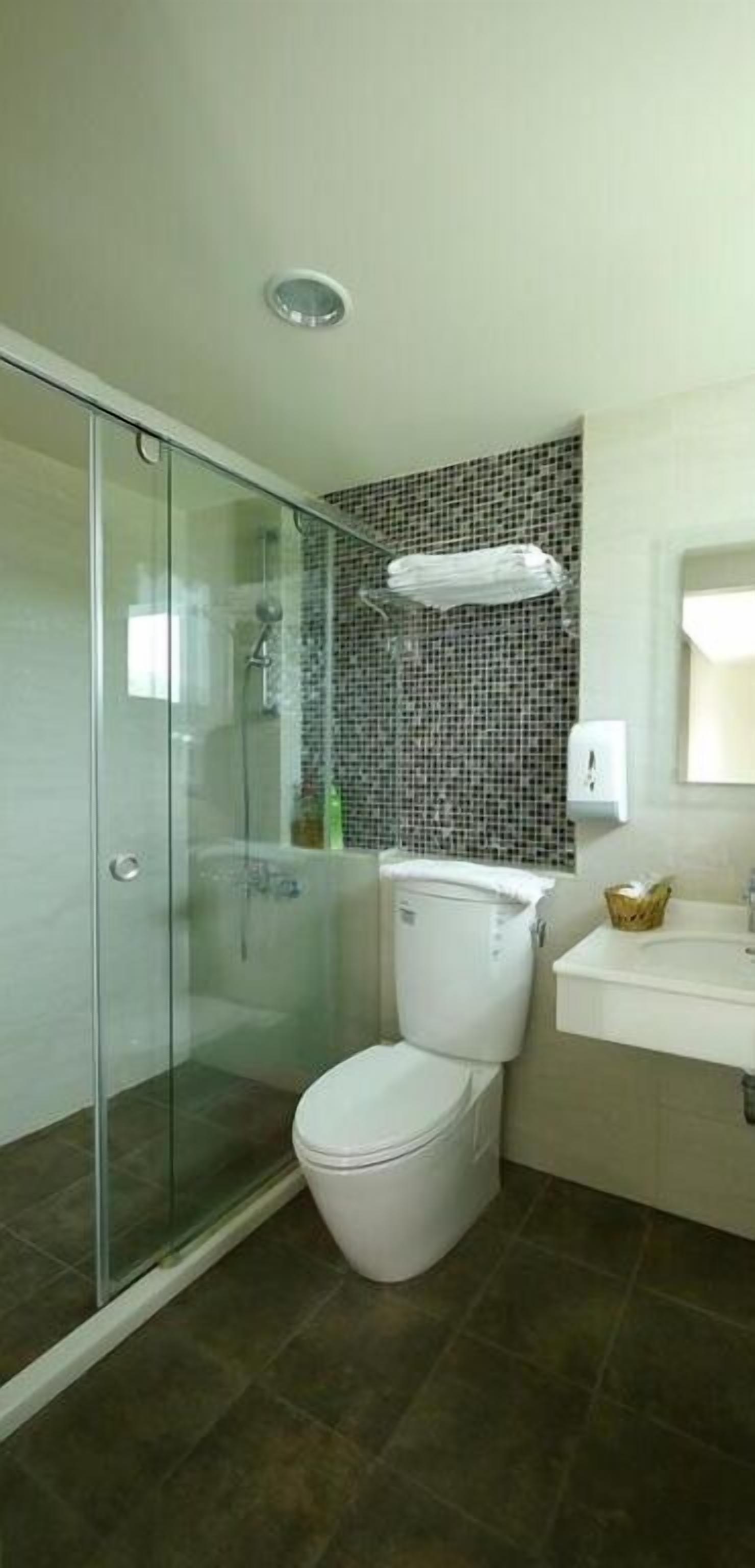 A bathroom with a glass shower enclosure, a toilet, and a sink.