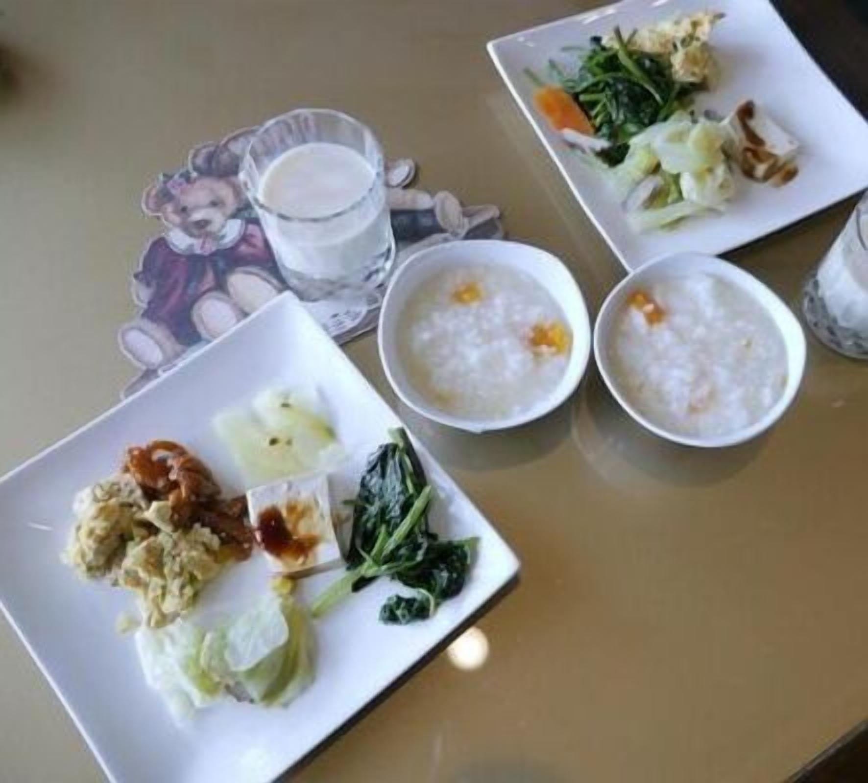 A table with three plates of food, a glass of milk, and a cup of tea.