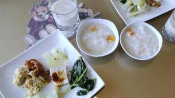 A table with three plates of food, a glass of milk, and a cup of tea.