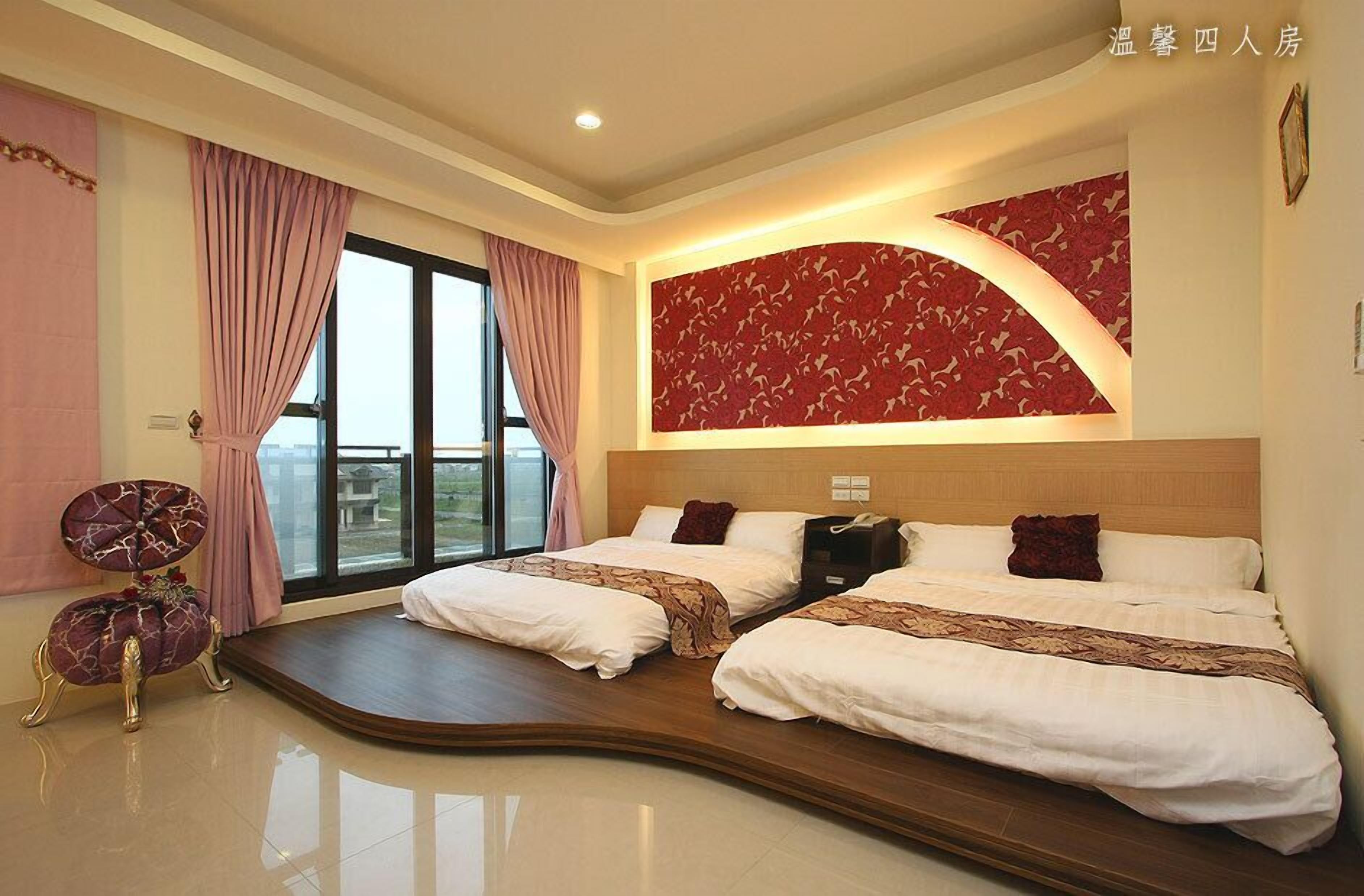 Habitación de hotel con dos camas, piso de madera curvada, un ventanal grande con cortinas y un panel decorativo en la pared.