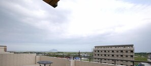 A balcony with a view of a distant island and a large building in the background. - Lambo Stay (Toucheng)