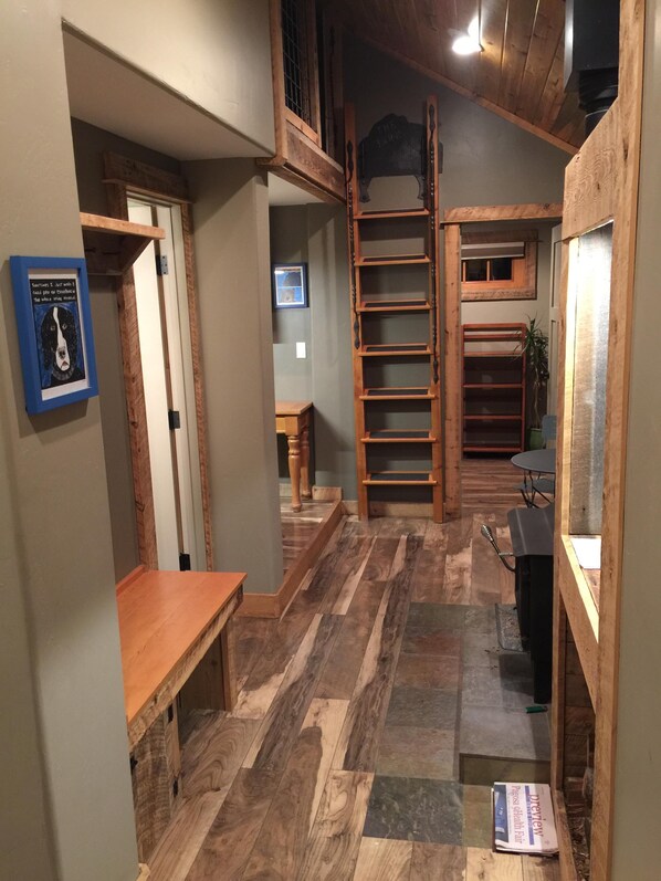 A narrow hallway with wooden flooring, a wooden bench, a ladder, and a framed picture on the wall. - PET FRIENDLY, cozy, quiet, cabin; river in the backyard STARLINK; VRP-25-0076 (Pagosa Springs)