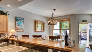 A kitchen with granite countertops, a sink, a dining area with chairs, and a chandelier.