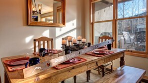 A dining table set with candles, plates, and a knife with a wooden handle.