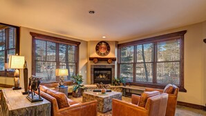 A living room with leather sofas, a fireplace, and large windows.