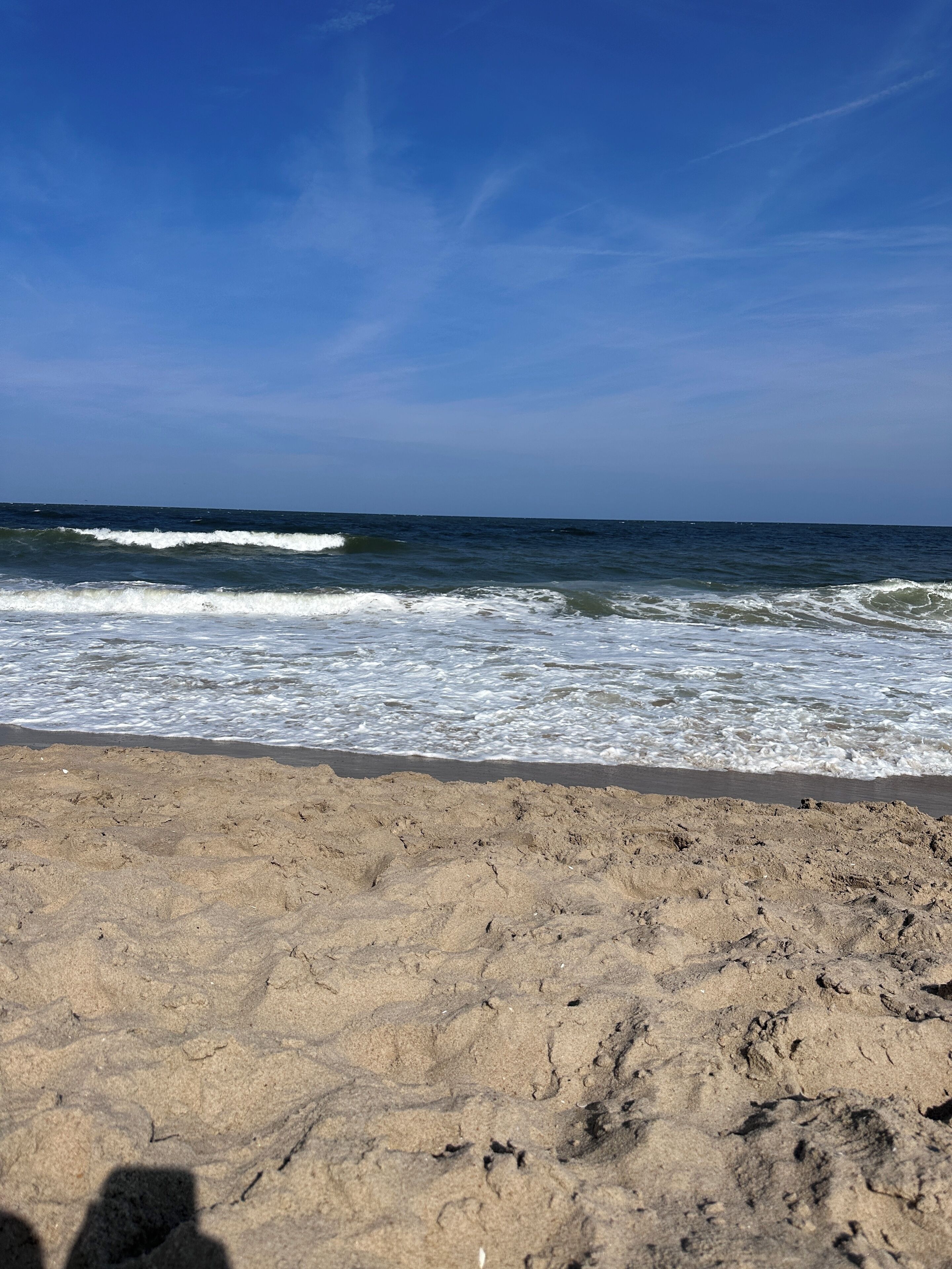 Una playa arenosa con olas acercándose a la orilla bajo un cielo despejado.