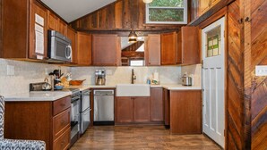 A kitchen with wooden cabinets, stainless steel appliances, and a window above the sink.