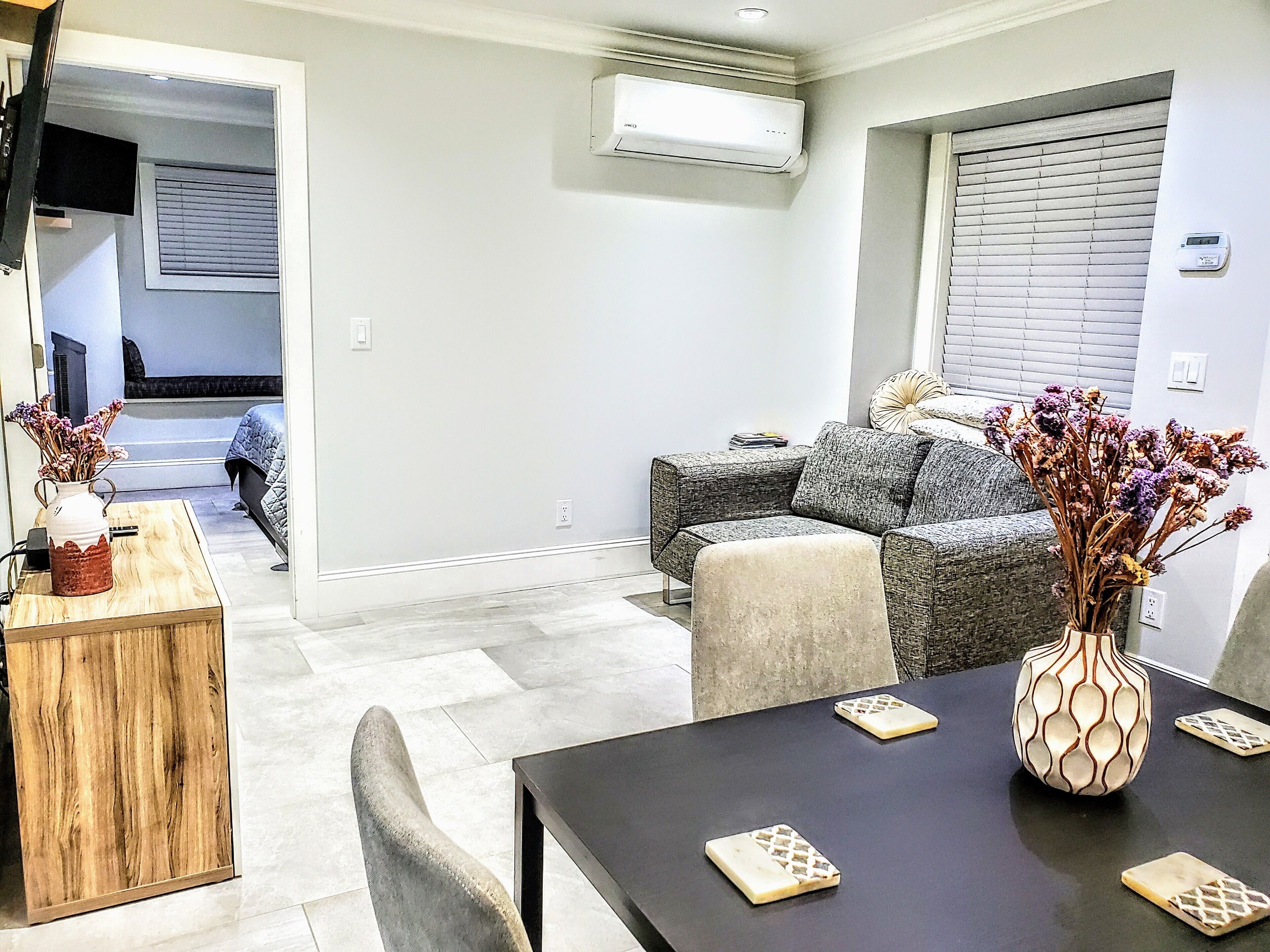 A modern living room with a grey sofa, a wooden coffee table, and a vase with dried flowers.