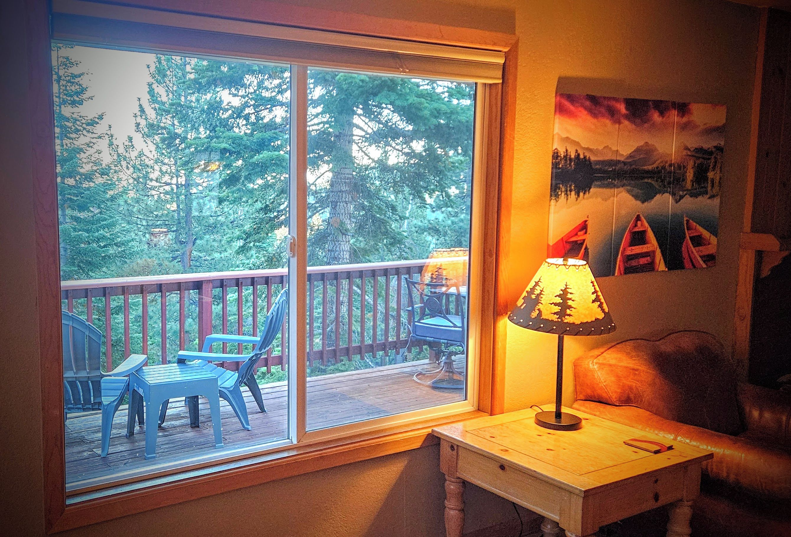 A room with a sliding glass door leading to an outdoor deck with chairs and a table.
