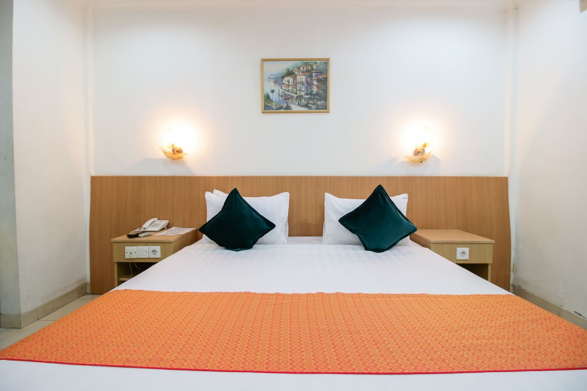 Ein Hotelzimmer mit einem großen Bett, zwei Nachttischen, einem Telefon und zwei Wandleuchten.