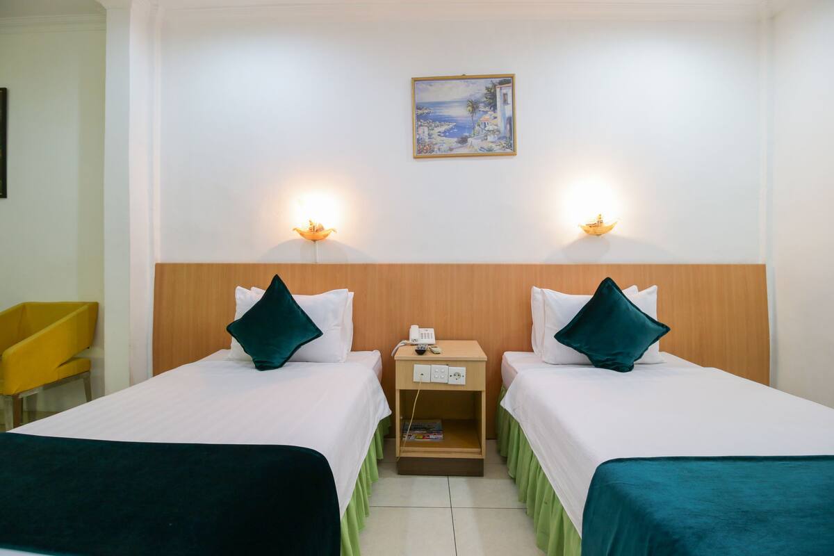 Ein Hotelzimmer mit zwei Betten, einem Nachttisch mit Telefon und einem Bild an der Wand.