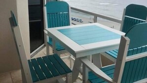 A balcony with a table and chairs, overlooking a beach. - Unit #802 Beautiful Spacious Beachfront Condo! Sleeps 10! New Updates!! <br> (Orange Beach)