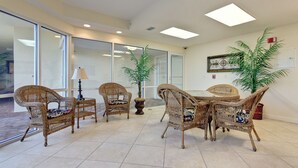 A spacious indoor area with wicker furniture, large windows, and a tiled floor. - Unit #802 Beautiful Spacious Beachfront Condo! Sleeps 10! New Updates!! <br> (Orange Beach)