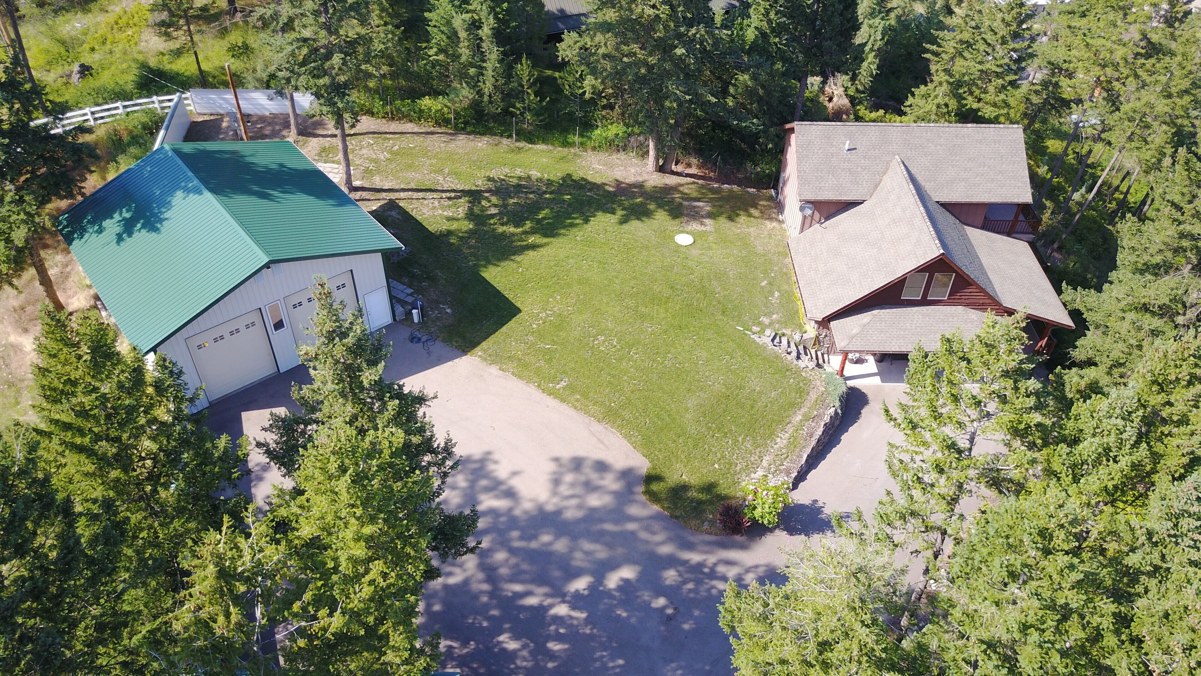 An aerial view of a property with a green-roofed building, a red-roofed building, and a well-maintained lawn.