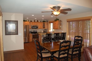 A kitchen with wooden cabinets, a stainless steel refrigerator, a microwave, and a dining table with chairs.