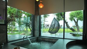 A modern bathroom with a large window, a bathtub, and a hanging chair outside. - Maple House Riverside (Dongshan)