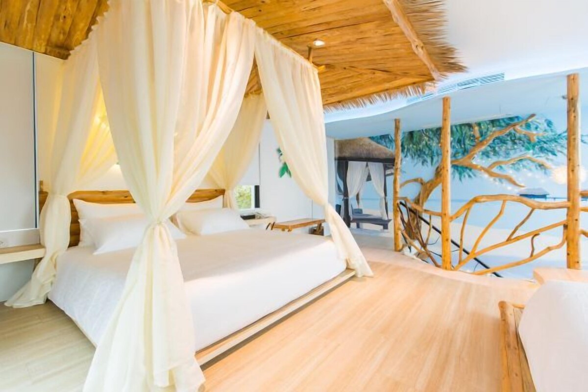 A room with a bed, a wooden ceiling, and a mural of trees.