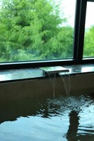 Una ventana con un elemento acuático y vistas a árboles.