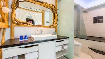 Un bany amb un mirall de fusta, un lavabo blanc i una cabina de dutxa de vidre.