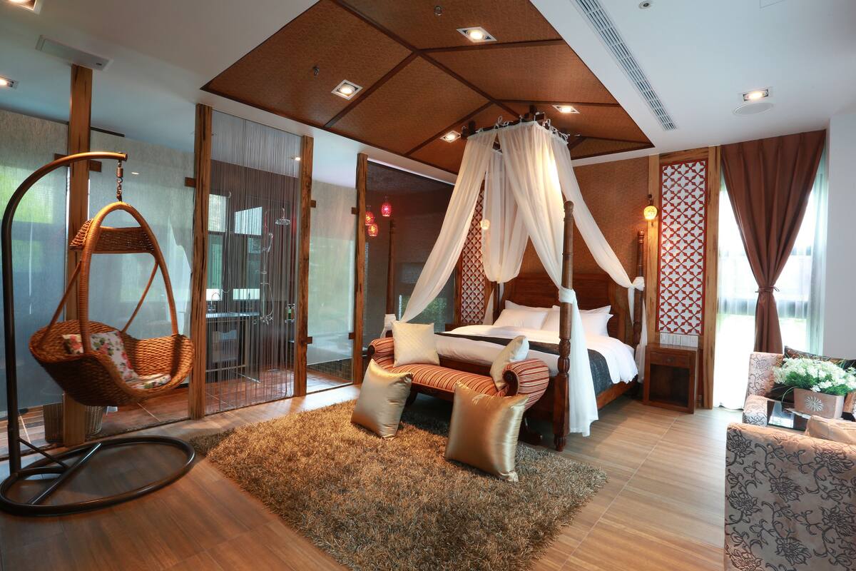 Quarto com cama de dossel, cadeira suspensa e uma janela grande com cortinas.