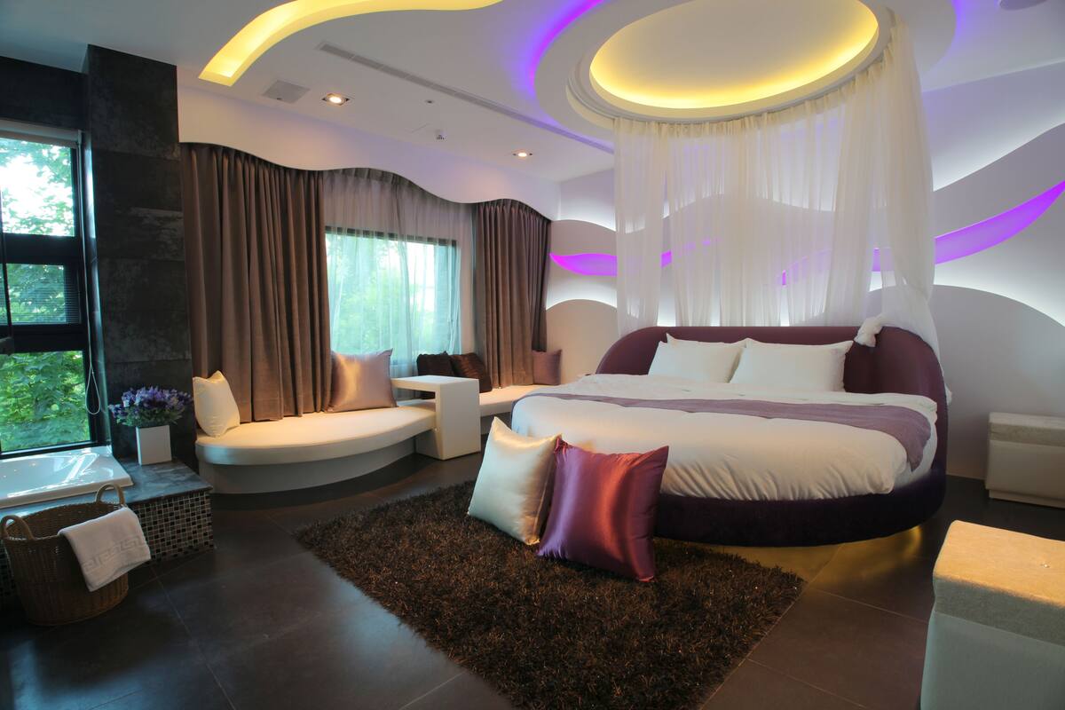 Quarto moderno com uma cama grande, área de estar e vista para o verde lá fora.