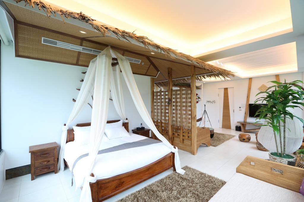 A modern bedroom with a canopy bed, a wooden headboard, a small bedside table, and a large potted plant.