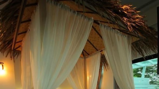A room with a bed under a canopy, a nightstand, a lamp, and a basket. - Maple House Riverside (Dongshan)