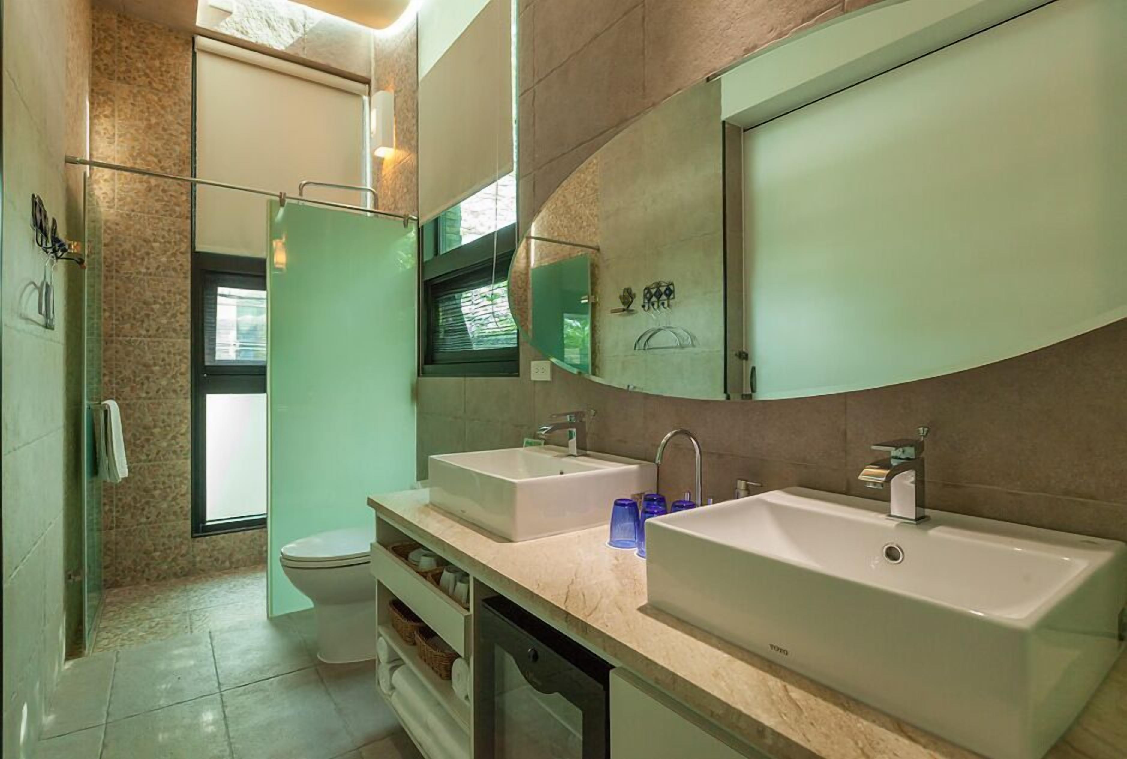 Un baño moderno con dos lavamanos, un inodoro y una zona de ducha.