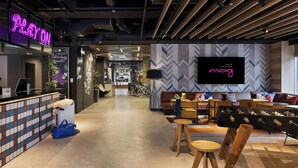 A modern interior with a reception area, seating, and a large TV screen. - Moxy Tokyo Kinshicho (Tokyo)
