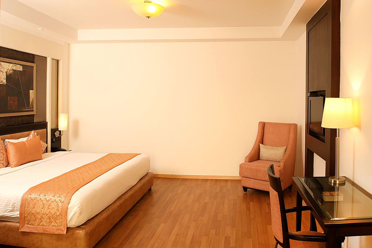 Una habitación de hotel con cama, una silla, un escritorio y una lámpara.